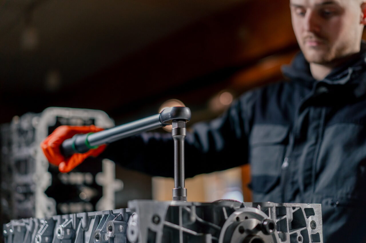 close-up At a service station in the hands of a master device for tightening bolts works with bolts on the engine