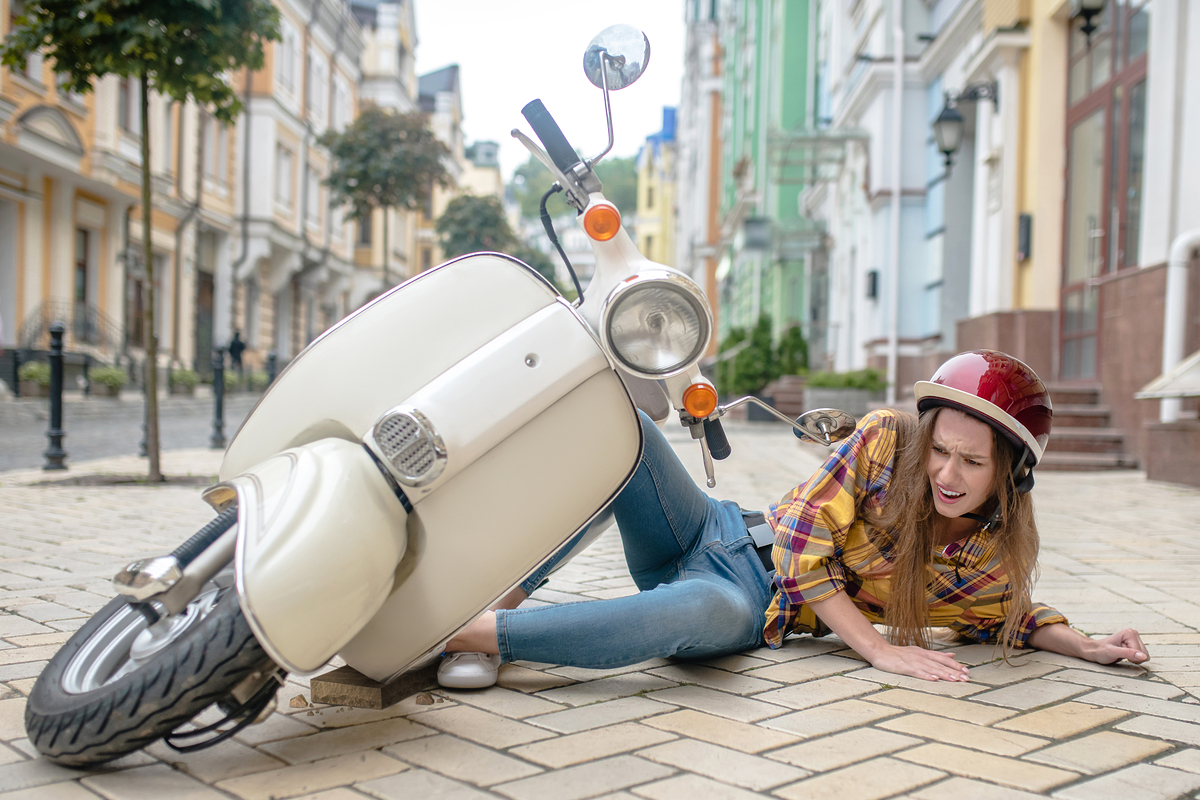 Danger. A woman falling from the scooter while having a first ride