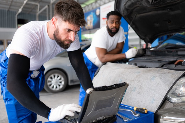 Both of professional auto mechanic working together in auto repair shop.